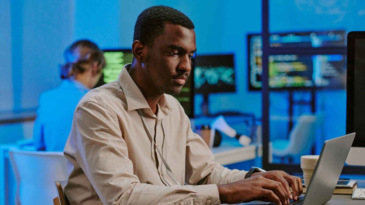A focused learner at a desktop screen in a bright workspace.